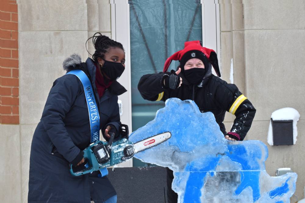 person holding chainsaw, person with thumbs up, and michigan ice sculpture